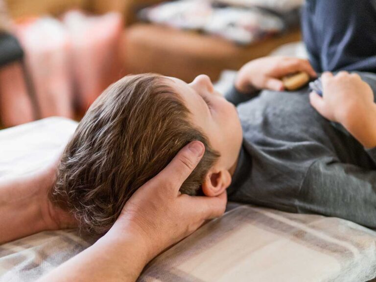 Adult receiving hands-on spinal care while a clinician discusses posture and movement in a bright treatment room.